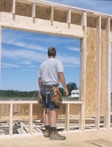 Man looking out of a window opening in a house under construction