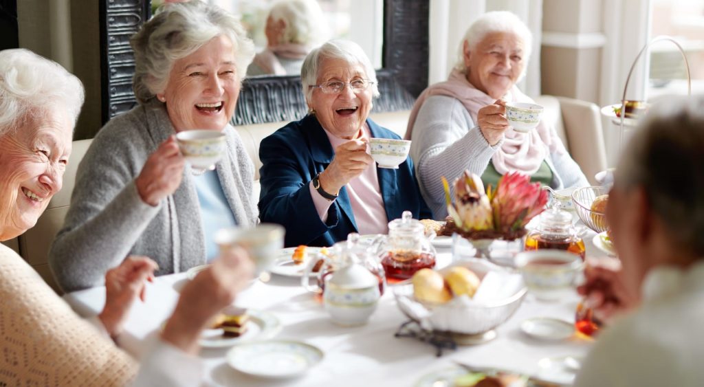 four women at table drinking coffee in a senior living community