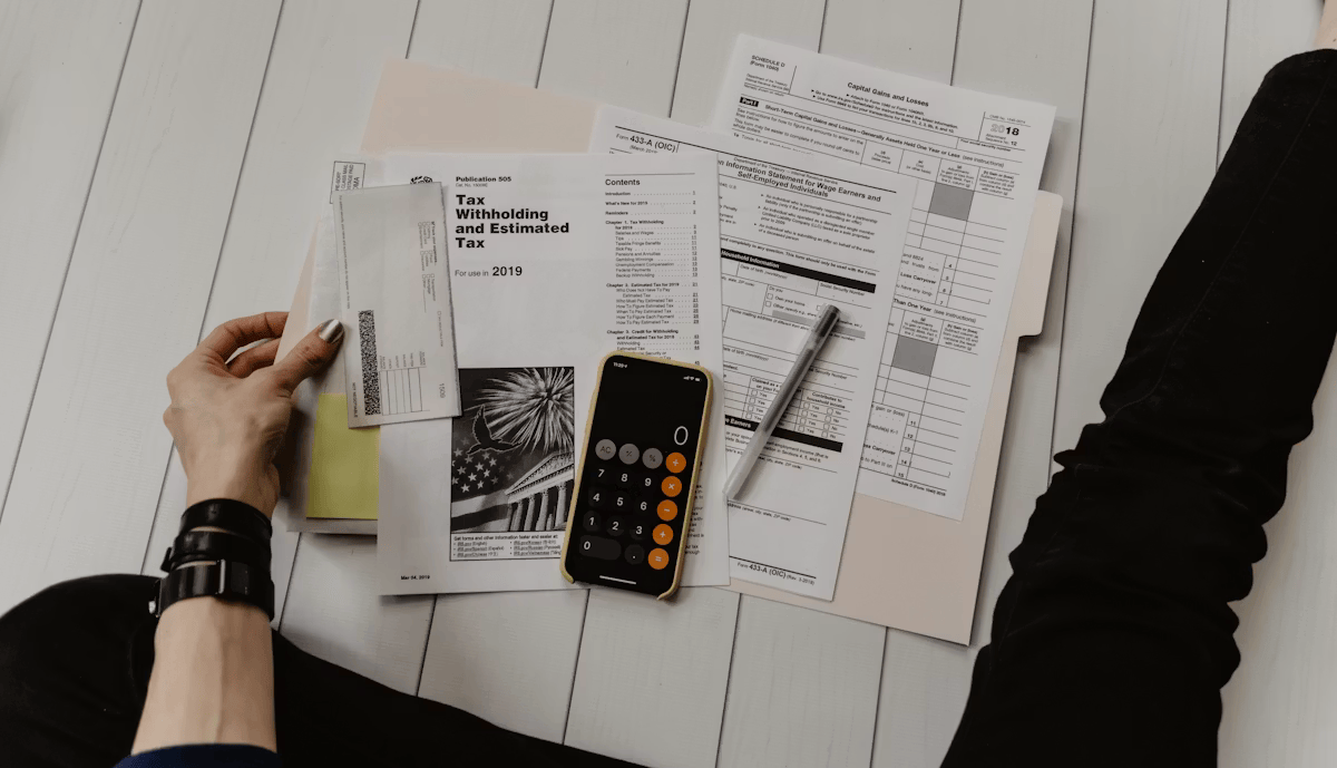 A person reviewing financial documents and tax forms with a calculator
